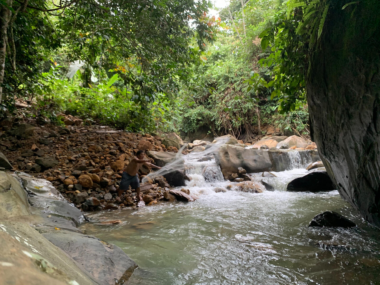 The hidden waterfall. The boulder can be seen on the right, and my father is casting his fishing net on the left.